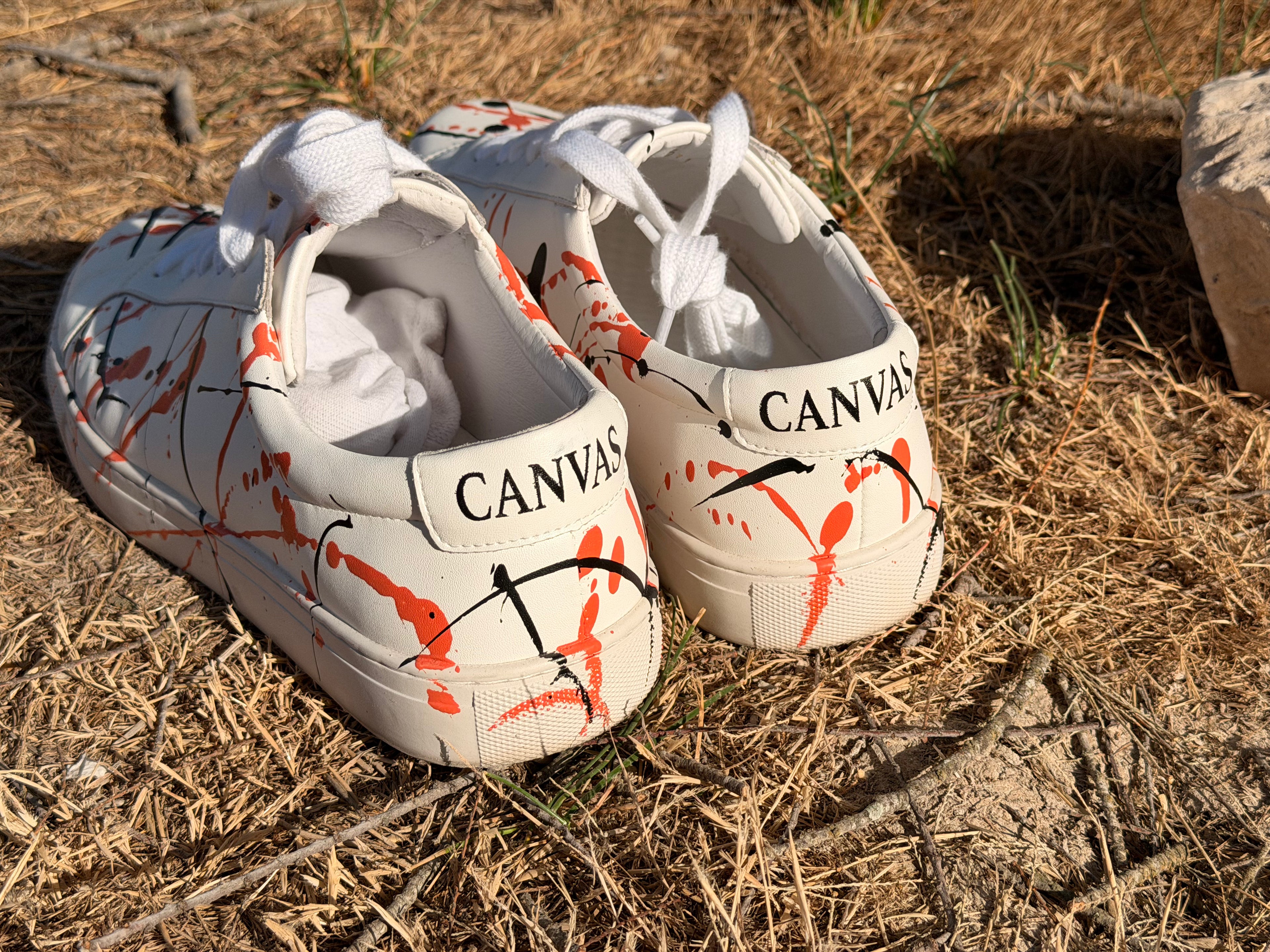 signal sneaker mit handgemachten farbspritzern auf einer Wiese im Urlaub